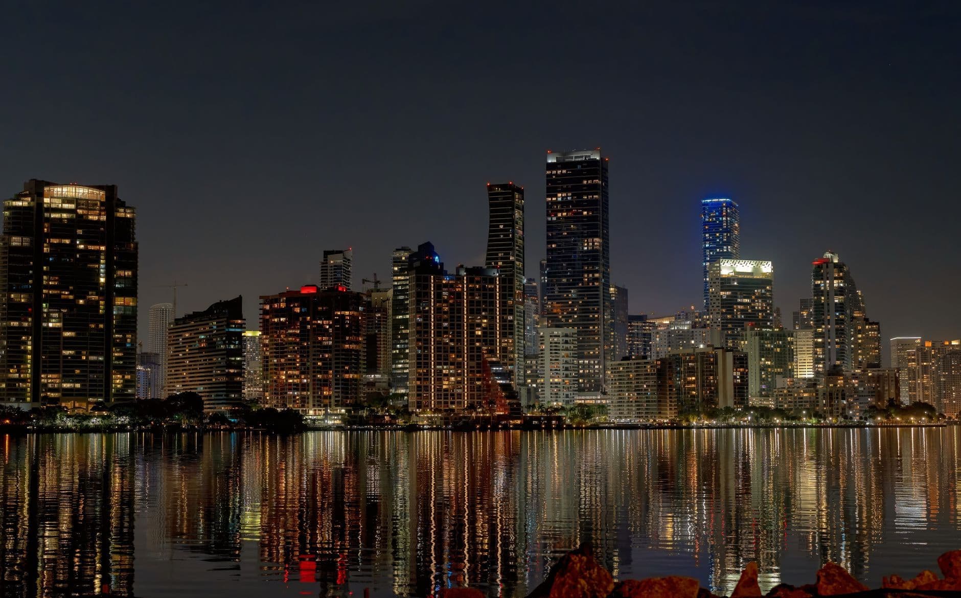 Explore the vibrant Miami skyline at night with stunning reflections in the water.